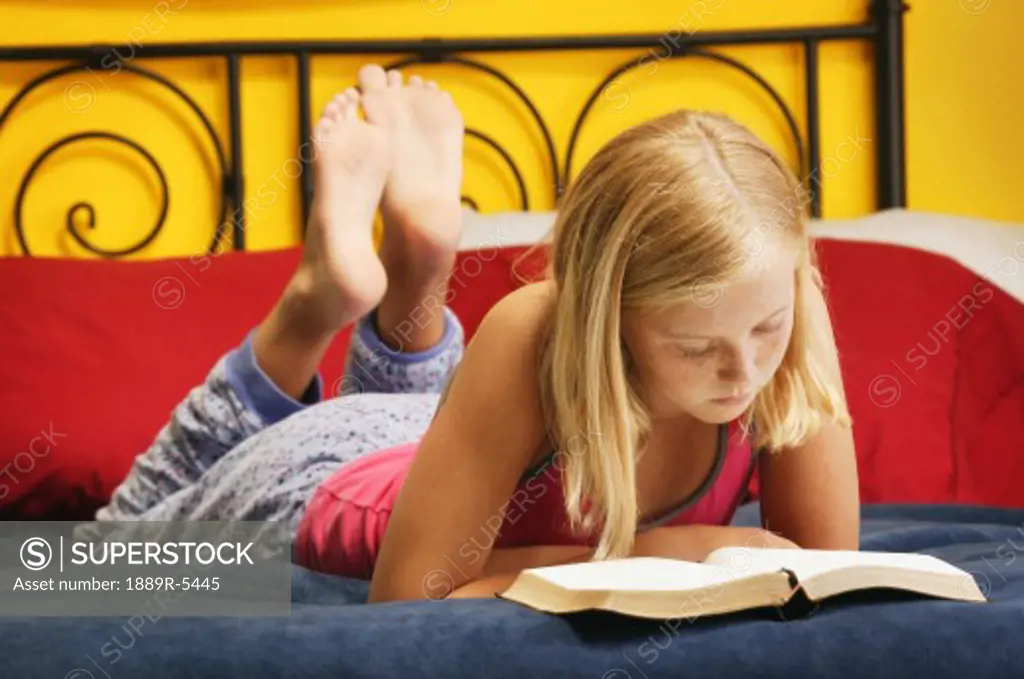Young girl reading bible on bed