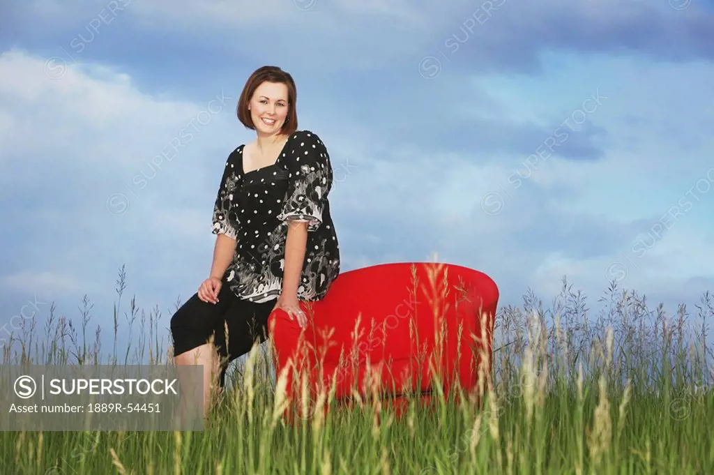 a woman sitting on a red chair in a field