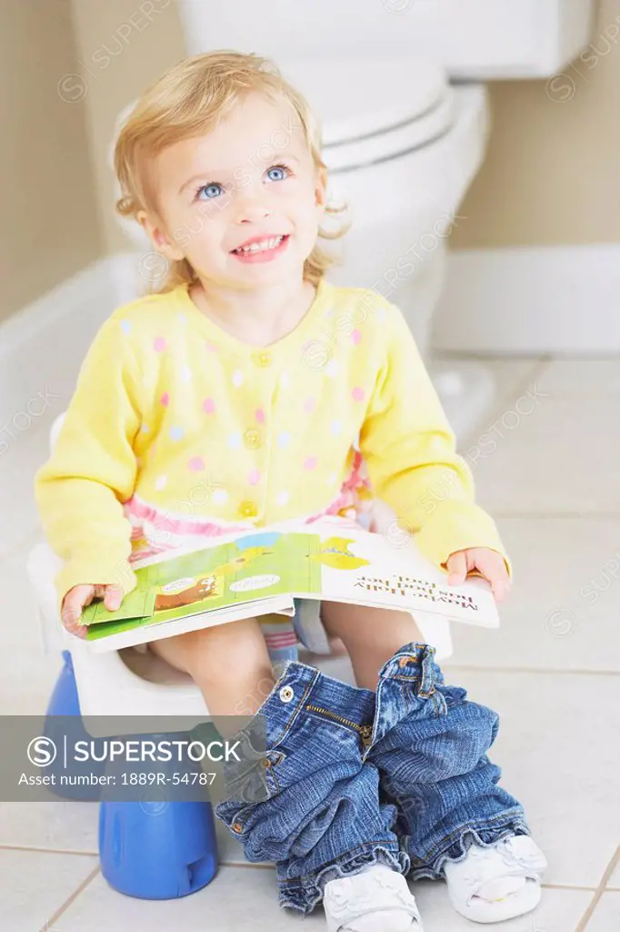 Knoxville, Tennessee, United States Of America, A Young Child Sitting On A Child´s Potty And Reading A Book