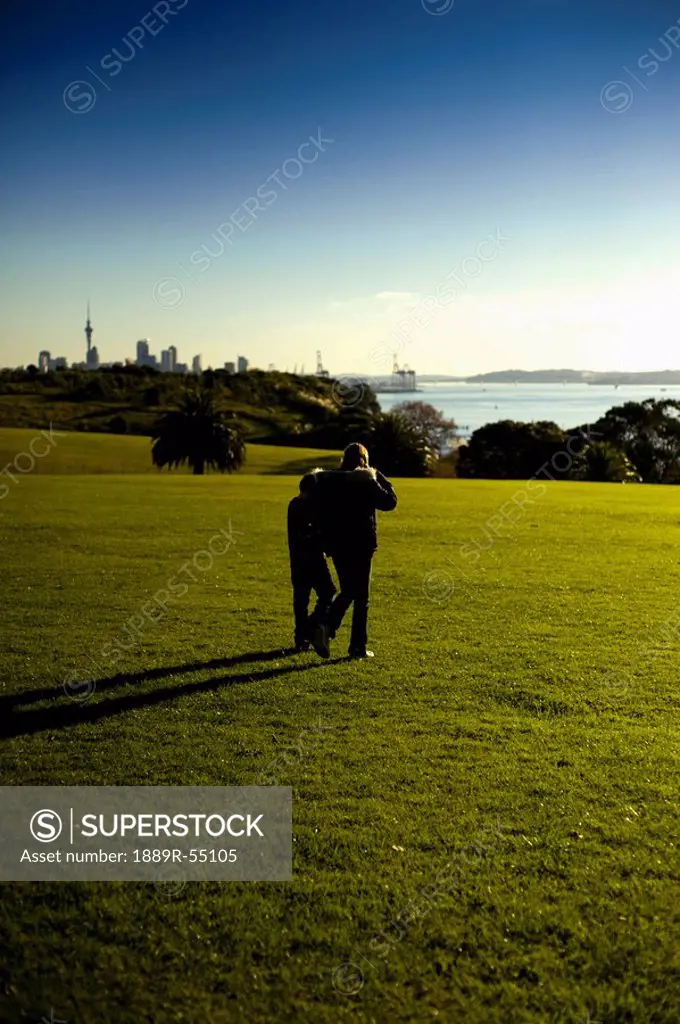 two people walking on a field towards the water