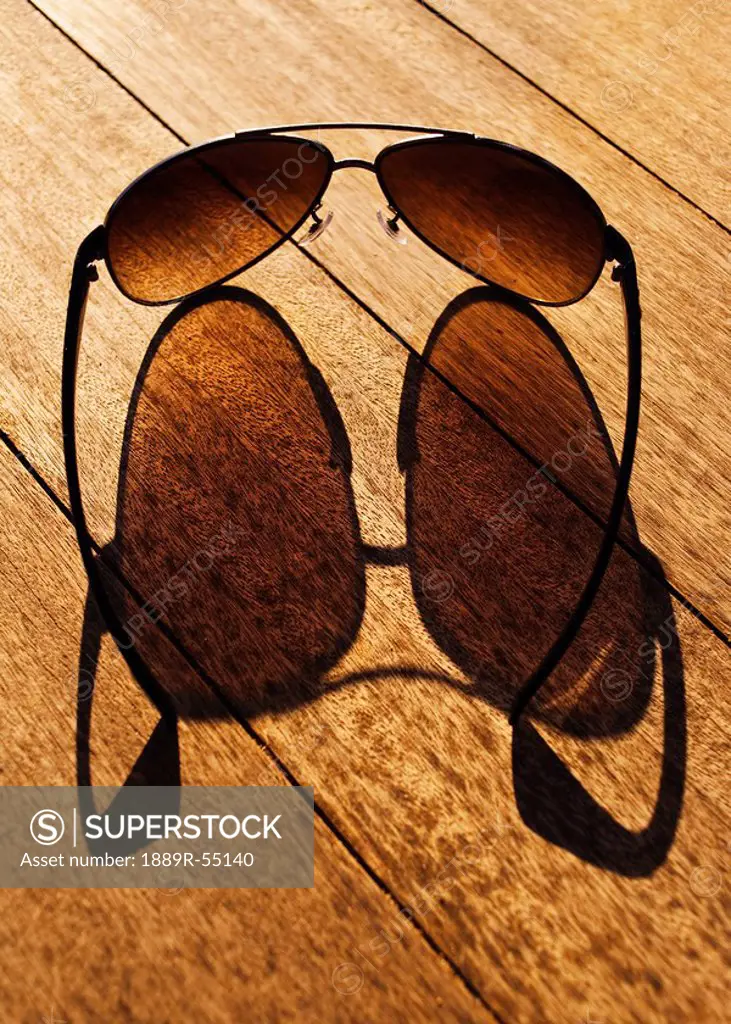 cadiz, spain, sunglasses casting their shadow on a wooden boardwalk