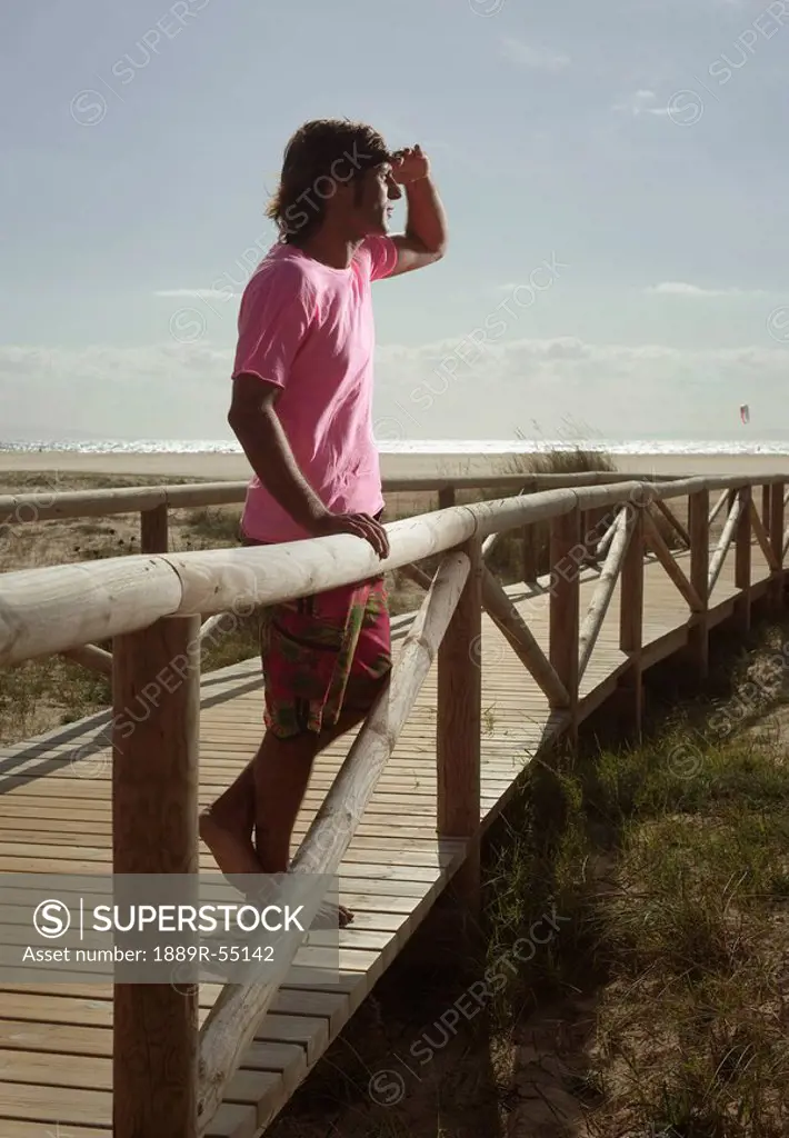 tarifa, costa de la luz, cadiz, andalucia, spain, a man stands at the railing of a boardwalk leading out to dos mares beach in front of hotel dos mare...