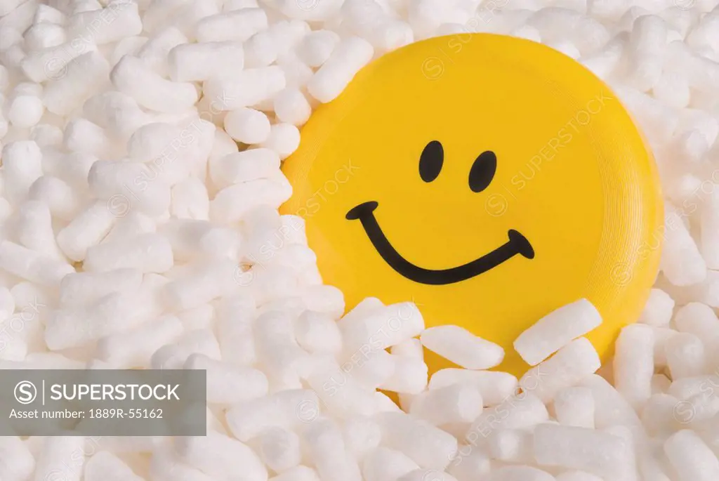 a yellow happy face in styrofoam packing peanuts