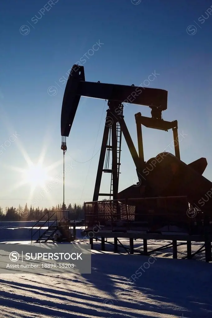 edson, alberta, canada, silhouette of a pump jack with a sunburst in winter