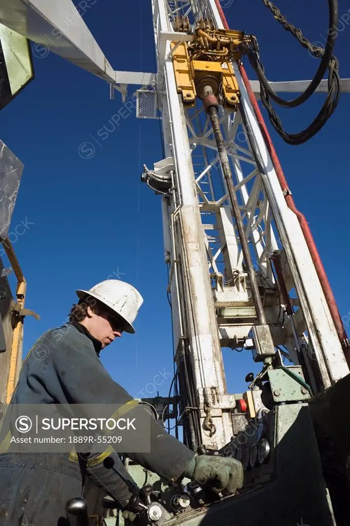 edson, alberta, canada, drilling rig worker working on the control panel on rig platform