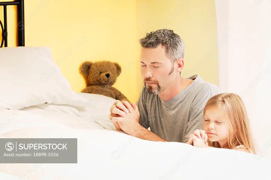 Father praying with daughter