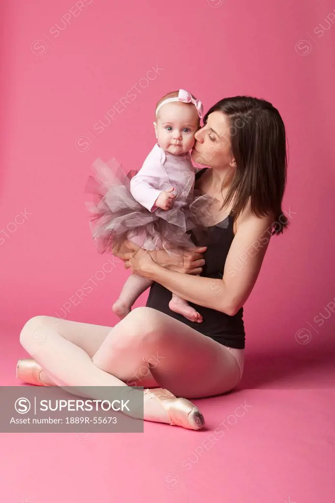 baby girl in tutu being kissed by her mother, a ballerina in pointe shoes