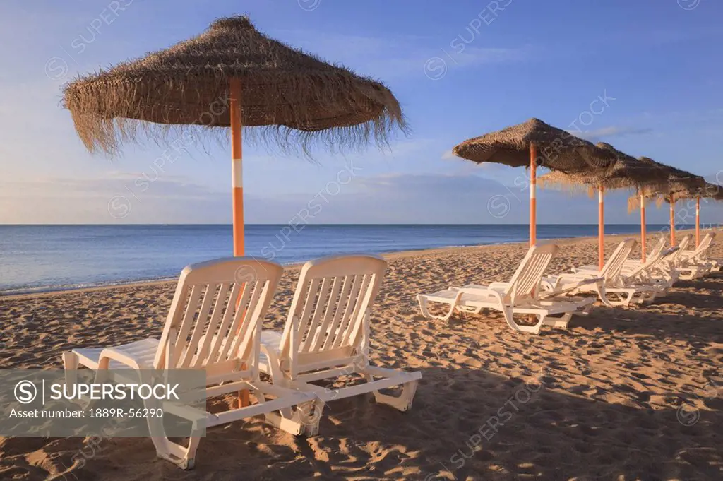 torremolinos, malaga, andalusia, spain, sun umbrellas and beach chairs on a beach in costa del sol