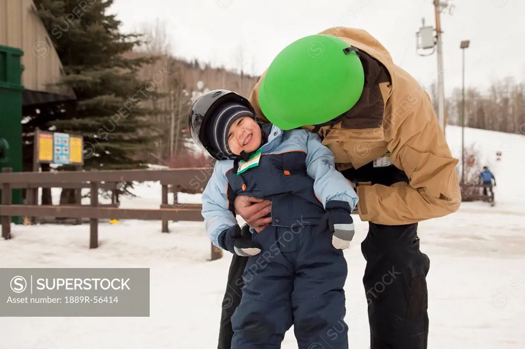 red deer, alberta, canada, a father and young son wearing helmets at a ski area