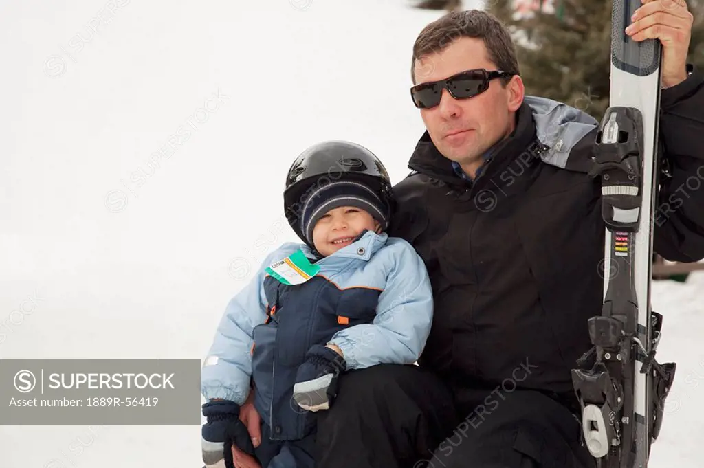 red deer, alberta, canada, a man with a young boy holding skis at a ski hill