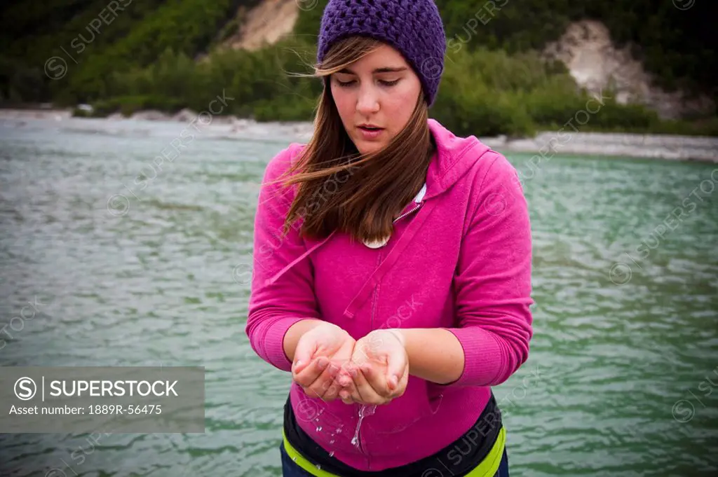 skagway, alaska, united states of america, a young woman holding clean water from the river in her cupped hands
