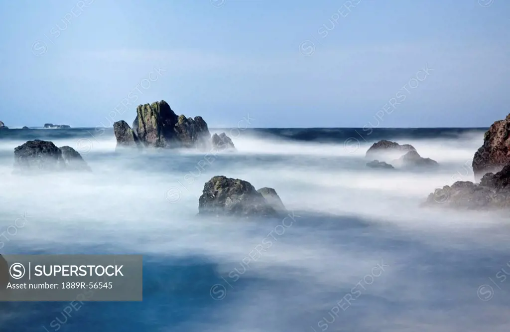 mist surrounding big rocks in the water, st. abb´s head, northumberland, england