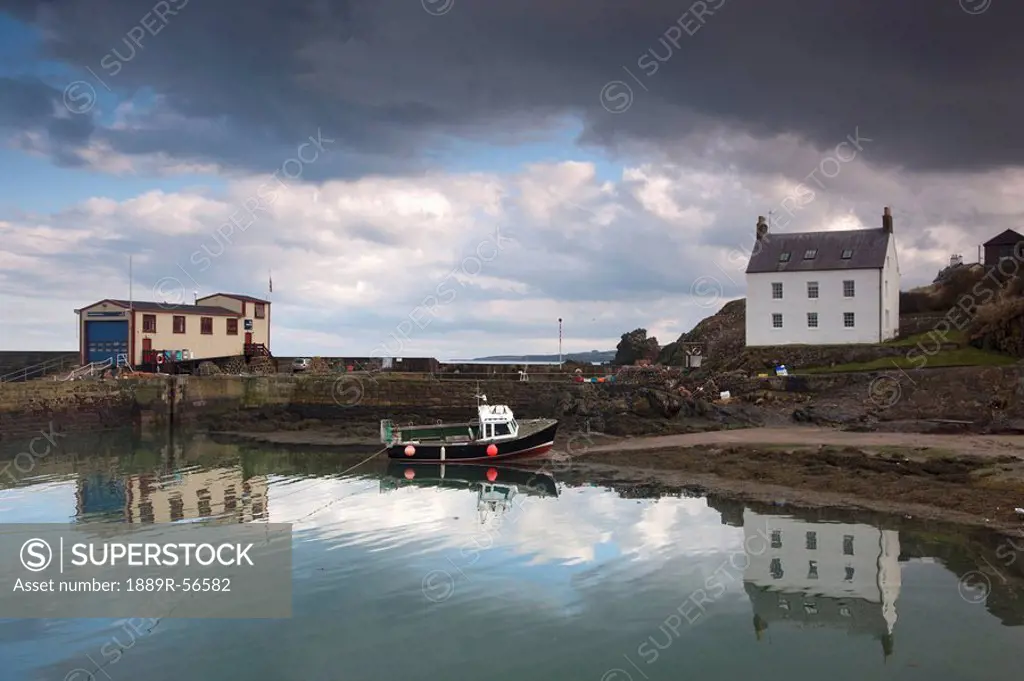 houses along the water and a boat on the shore, st. abb´s head, scottish borders, scotland