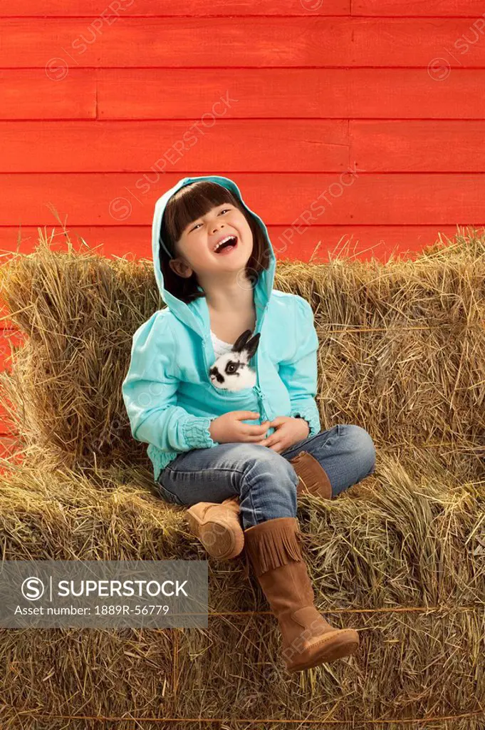 three hills, alberta, canada, a girl sitting on hay bales holding a bunny rabbit