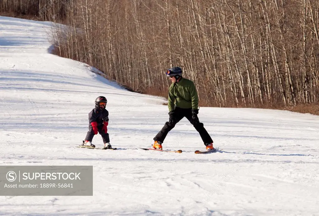 red deer, alberta, canada, a father teaches his young son how to ski