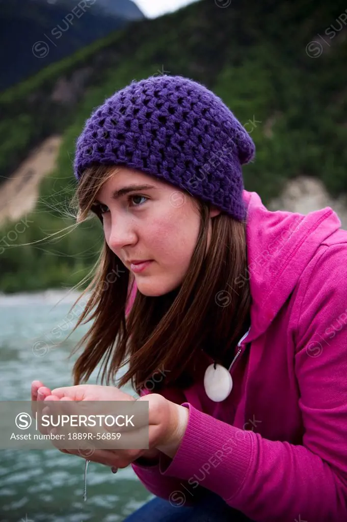 skagway, alaska, united states of america, a young woman cups her hands and drinks water from a river