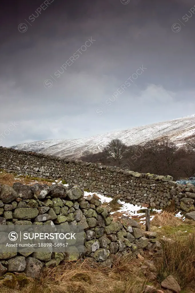 a stone wall with snow covering the hills, scottish borders, scotland