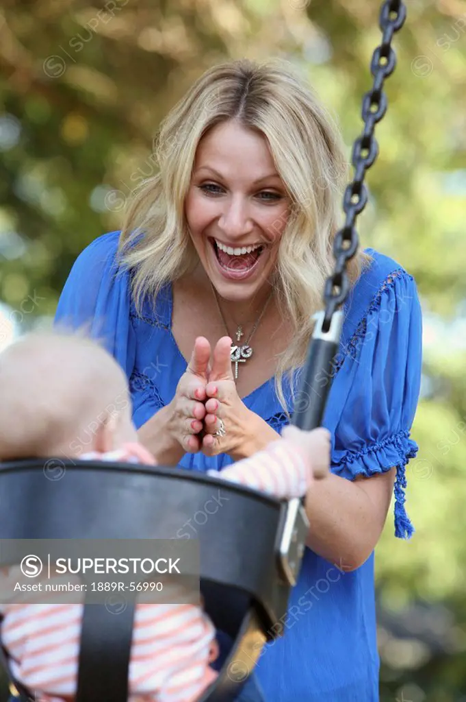 a mother playing with her baby in a swing, gresham, oregon, united states of america