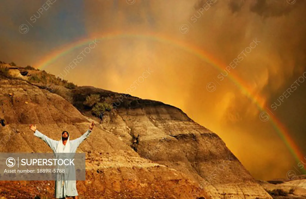 Man with outstretched arms, rainbow in background