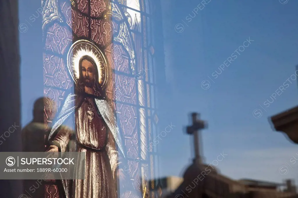 Buenos Aires, Argentina, A Stained Glass Window Depicting Jesus With A Reflection Of A Cross In Recoleta Cemetery