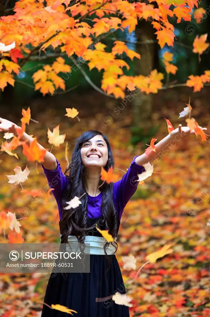 Portland, Oregon, United States Of America, A Teenage Girl Throwing Autumn Colored Leaves In The Air