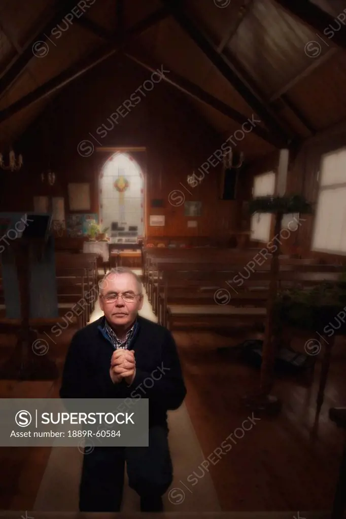 Northumberland, England, A Man On His Knees Praying At The Altar Of A Church