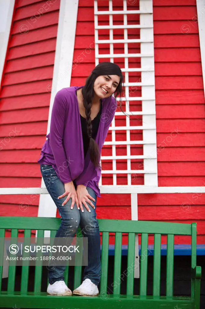 Woodburn, Oregon, United States Of America, A Teenage Girl Poses On A Green Bench In Front Of A Windmill At Wooden Shoe Tulip Farm