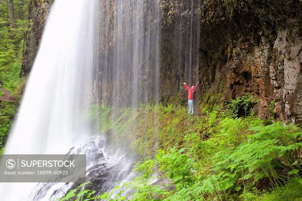 Oregon, United States Of America, A Person With Their Arms Stretched Upwards Standing Behind North Middle Falls In Silver Falls State Park