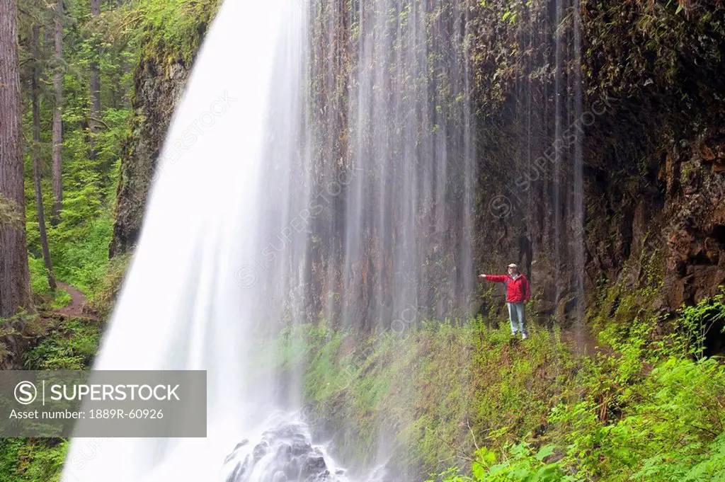 Oregon, United States Of America, A Person Reaching Out To Touch As They Stand Behind North Middle Falls In Silver Falls State Park