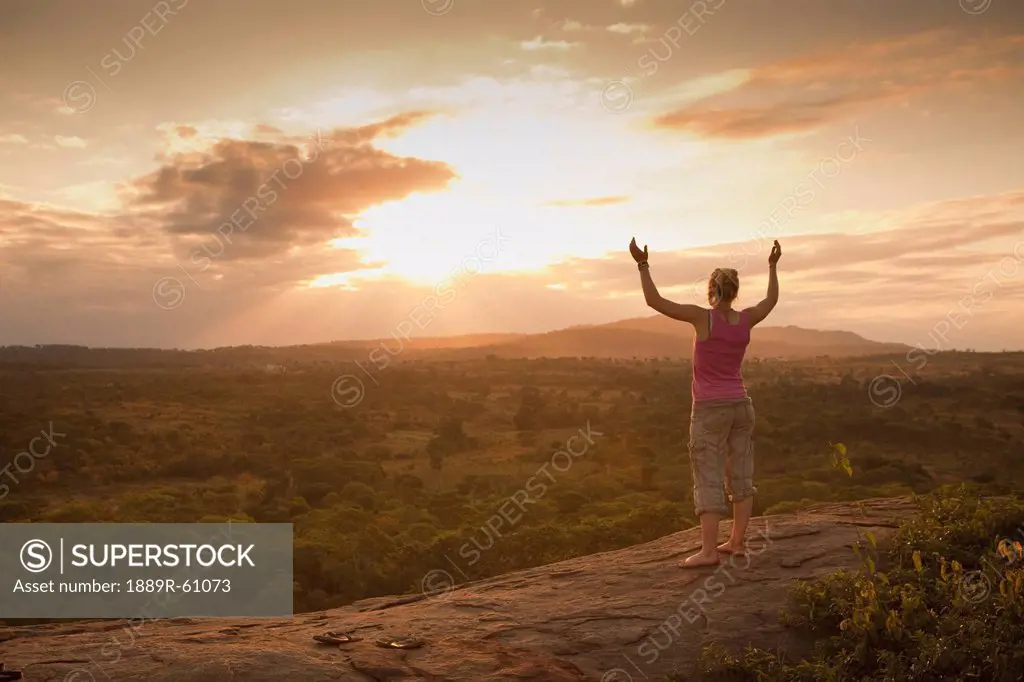 A Young Woman Looking Over The African Landscape With Arms Raised, Manica, Mozambique, Africa