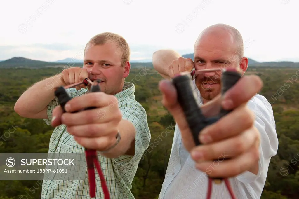 Two Men Pointing Slingshots At The Camera, Manica, Mozambique, Africa