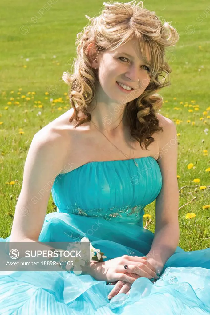 A Young Woman In A Formal Dress Sitting On The Grass, Camrose, Alberta, Canada