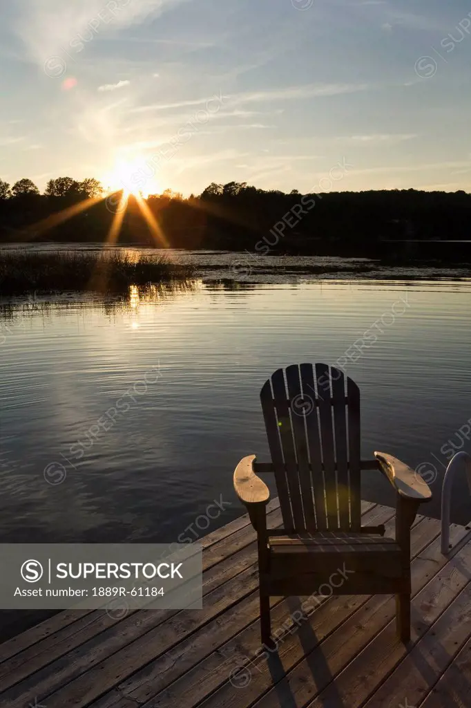 Sunset On A Lake With A Dock And Wooden Arm Chair, Flesherton, Ontario, Canada