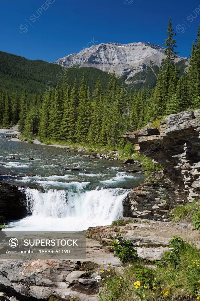 Waterfalls With Rock Ledge And Mountain In The Background, Alberta, Canada