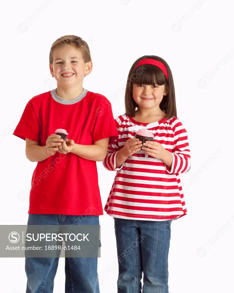 Two Children Wearing Red And Holding Cupcakes