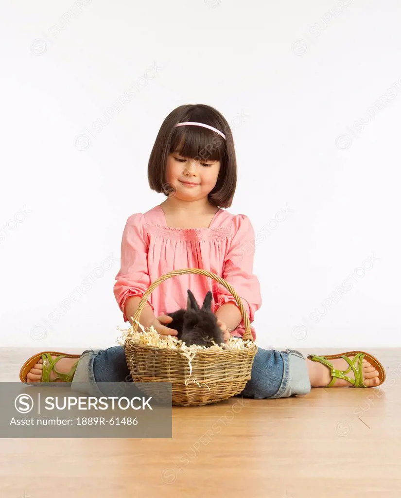 A Girl Petting A Rabbit In A Basket