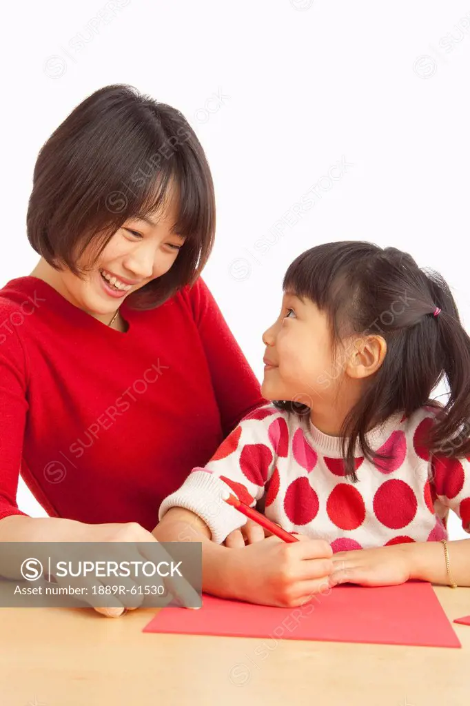 A Mother And Daughter Writing A Note On Red Paper