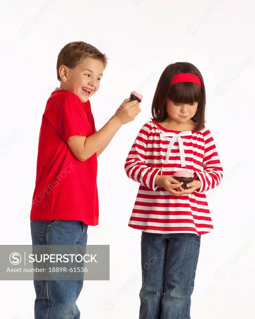 A Boy Teasing A Girl With His Chocolate Cupcake