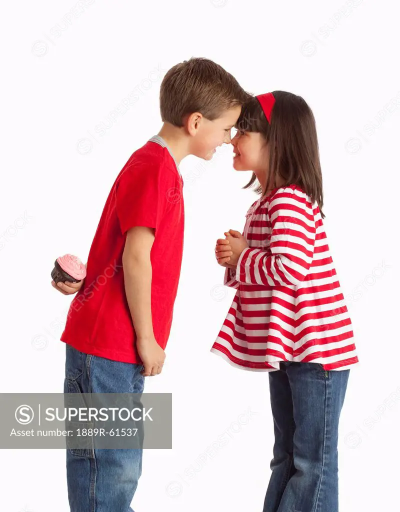 A Boy Hiding A Cupcake Behind His Back To Give To A Girl