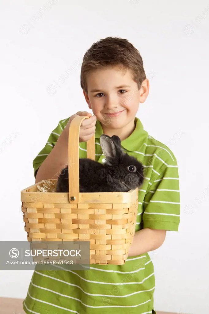A Boy Holding A Basket With A Rabbit In It