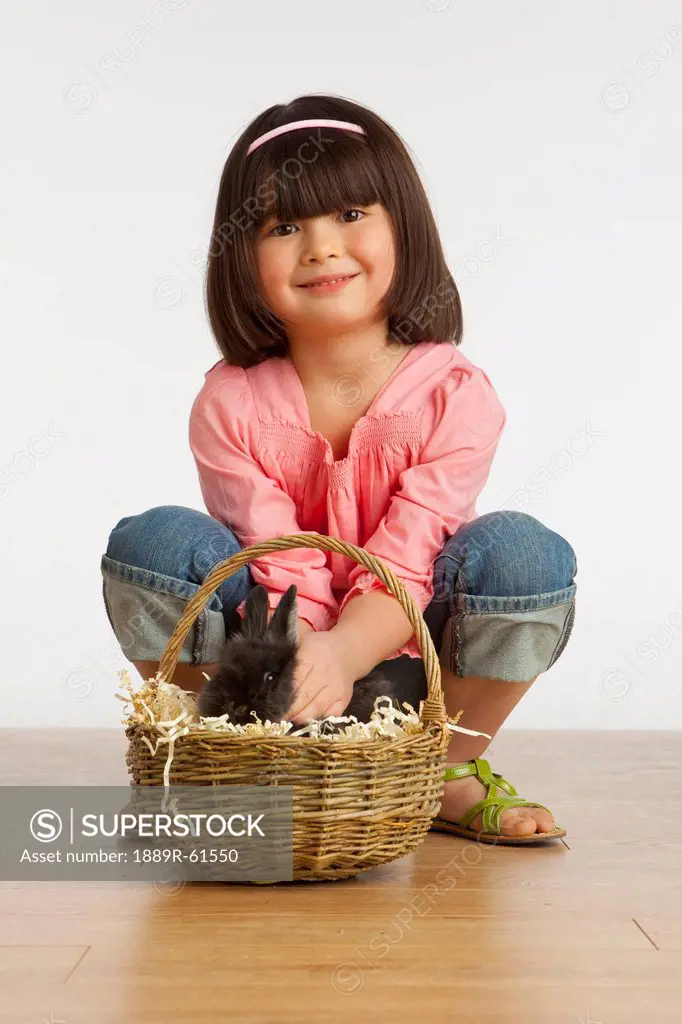 A Girl Petting A Rabbit In A Basket