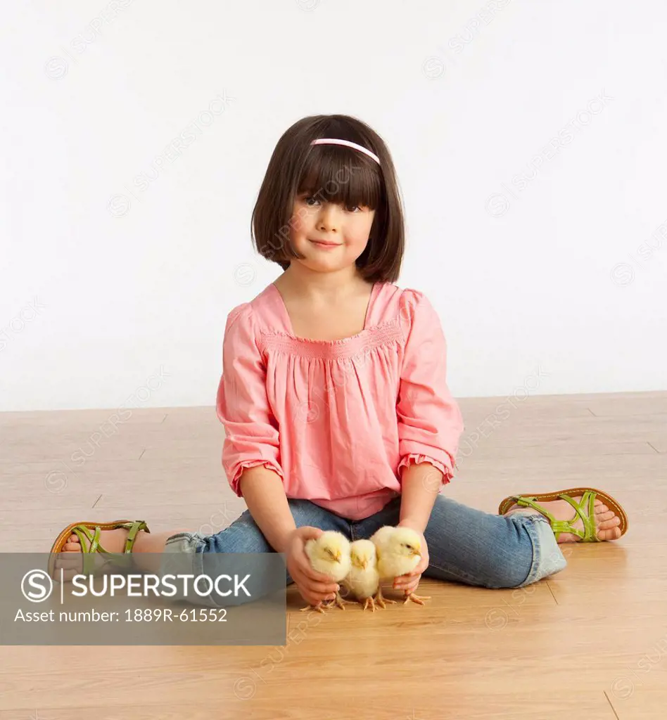 A Girl Sitting On The Floor With 3 Chicks
