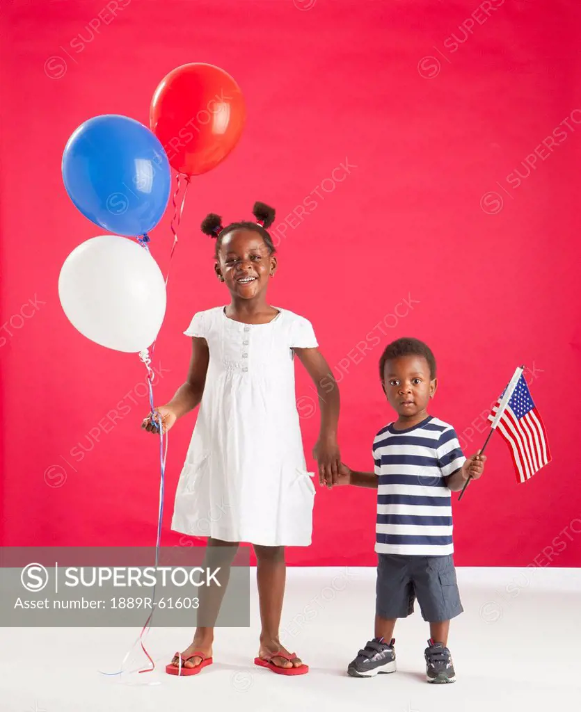 A Girl And Boy Holding Red, White And Blue Balloons And An American Flag