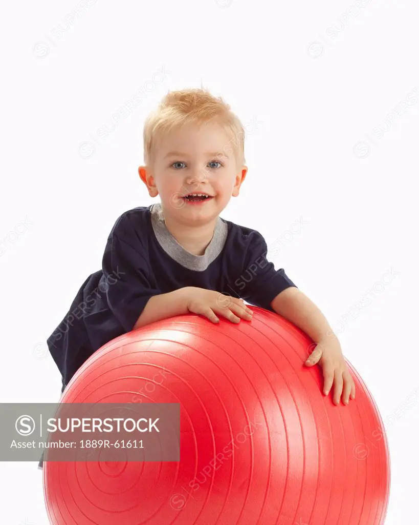 A Boy Leaning On A Large Red Ball