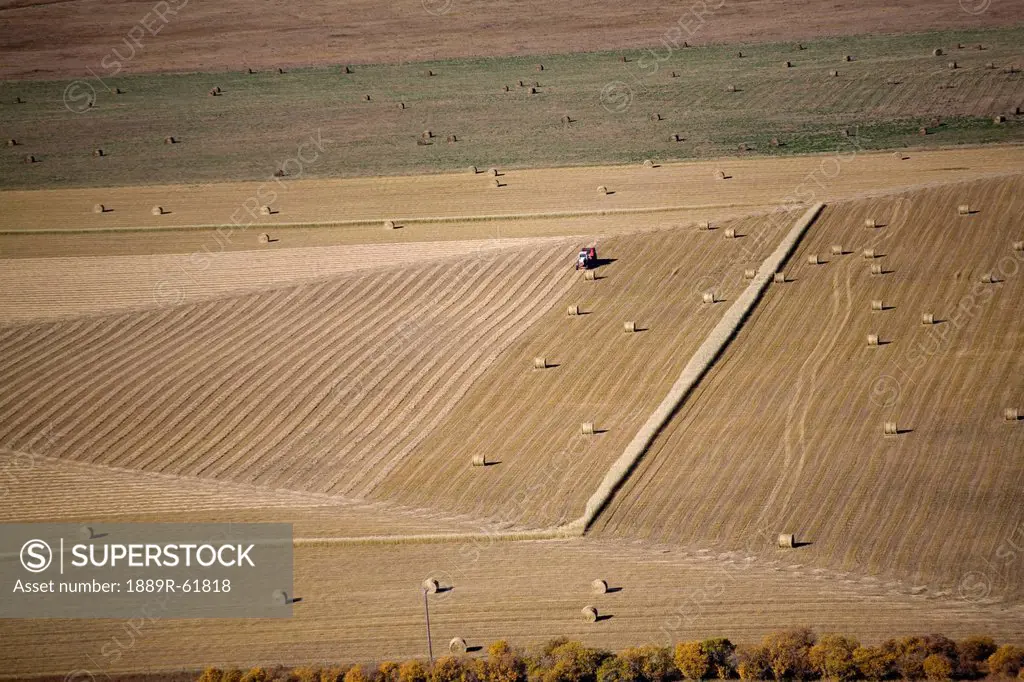 aerial view of a field with hay bales and a baler, alberta, canada