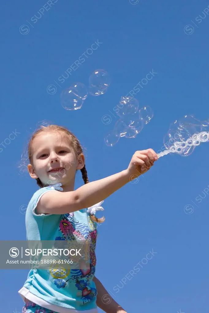 girl playing with bubbles against a blue sky, portland, oregon, united states of america