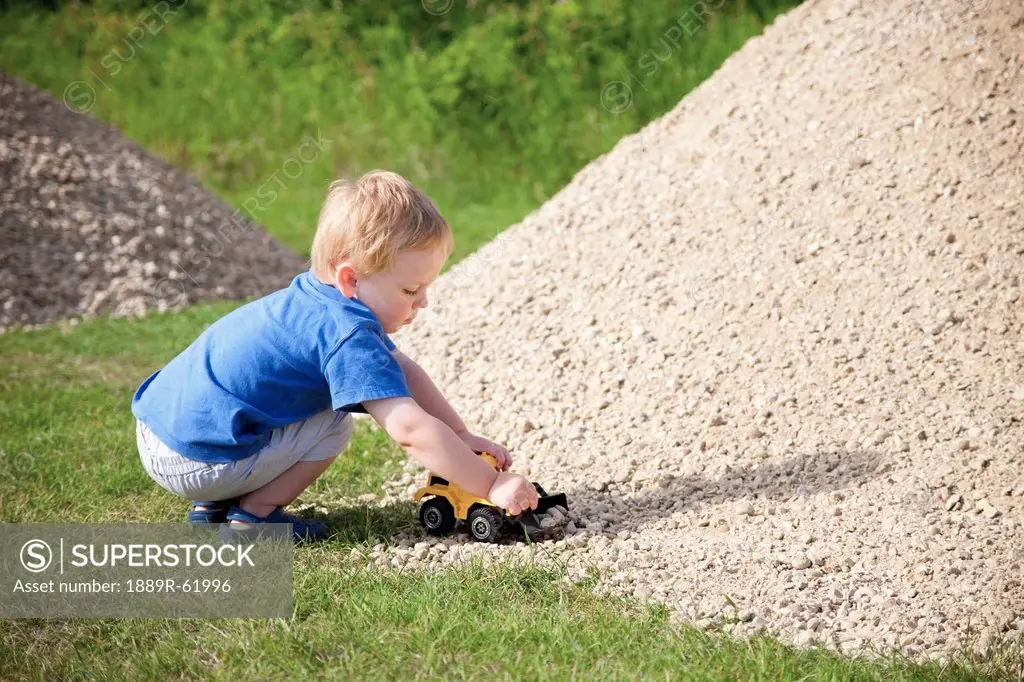 a young boy drives his toy truck through a rock pile, edmonton, alberta, canada
