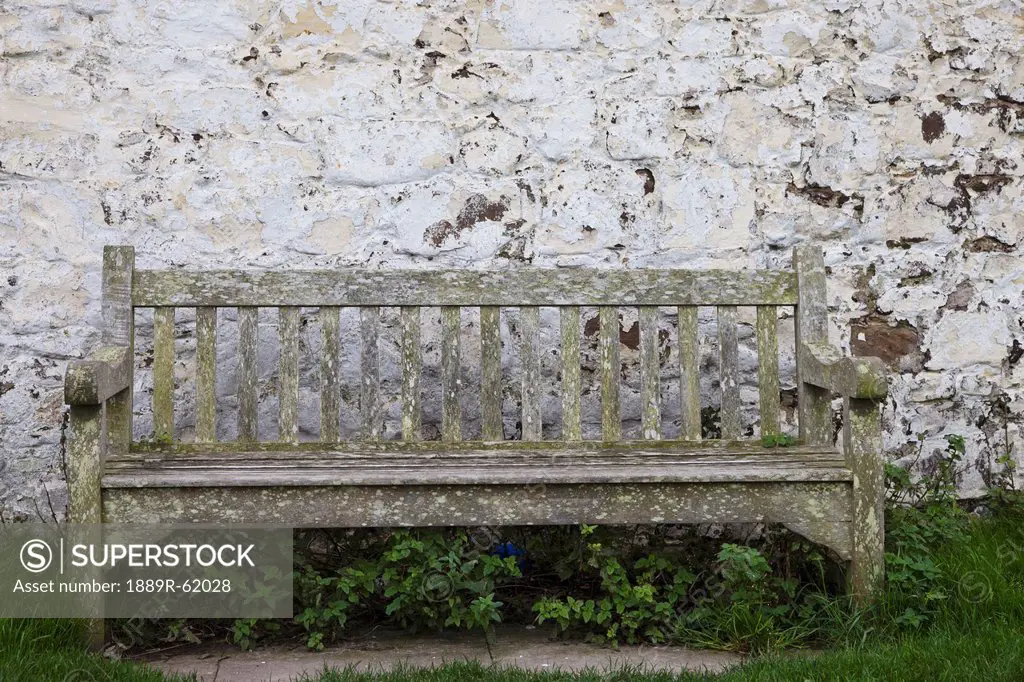 a wooden bench with peeling paint against a white wall, northumberland, england