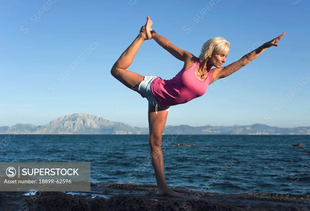 a woman doing a yoga pose in parque natural del estrecho, tarifa, cadiz, andalusia, spain