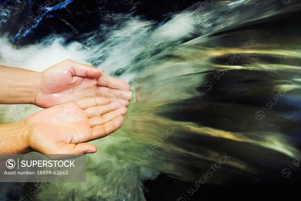hands held out to catch water at the currumbin rock pools in the currumbin valley, gold coast, queensland, australia